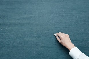 Hand schreibt mit Kreide auf Tafel